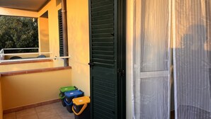 Ein Balkon mit Metallgeländer, einer grünen Tür und Aufbewahrungsboxen.