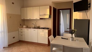 Une cuisine compacte avec des meubles blancs, une cuisinière à gaz et un petit coin repas comprenant une table et des chaises.