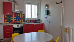 A kitchen with red cabinets, a white stove, and a window with blinds. - Special Guest Home (BARI)