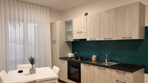 A modern kitchen with light wood cabinets, a black countertop, and a teal backsplash.