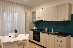 Una cocina moderna con armarios de madera clara, encimera negra y salpicadero verde azulado.