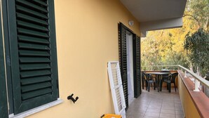 Un balcon avec un sol carrelé, une table avec des chaises et une rambarde.