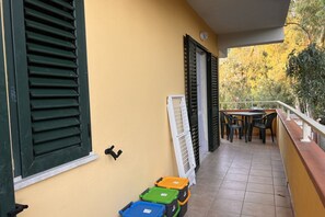 Un balcón con suelo de baldosas, una mesa con sillas y una barandilla.