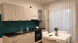 Eine moderne Küche mit hellen Holzschränken, einer schwarzen Arbeitsplatte und einer türkisblauen Spritzschutzwand.
