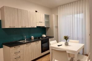 Eine moderne Küche mit hellen Holzschränken, einer schwarzen Arbeitsplatte und einer türkisblauen Spritzschutzwand.