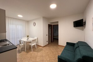 A compact living space with a kitchenette, a dining area, and a sofa.