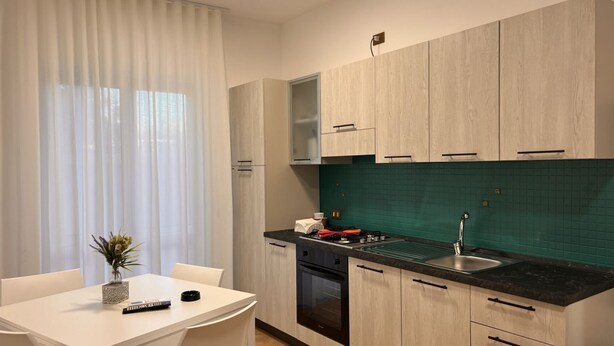 Une cuisine moderne avec des meubles en bois clair, un plan de travail noir et un revêtement mural vert.