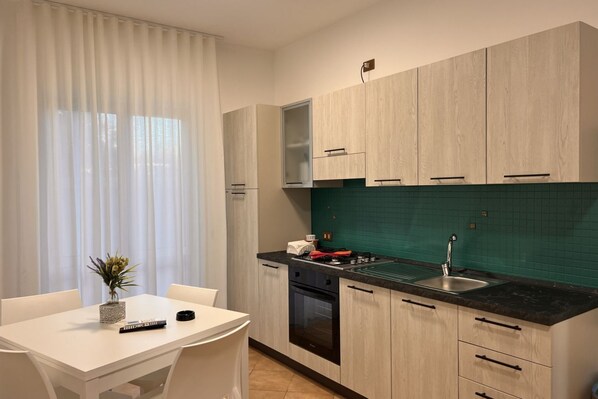 Een moderne keuken met lichte houten kastjes, een zwart aanrecht en een groene spatwand.