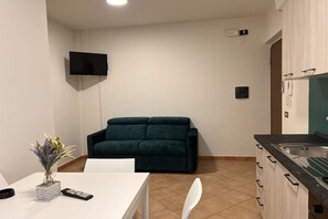 Un espacio habitable funcional con kitchenette, un sofá y zona de comedor.