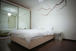 Una camera da letto con un letto, un comodino, uno specchio e una decorazione a forma di ramo appesa al muro.