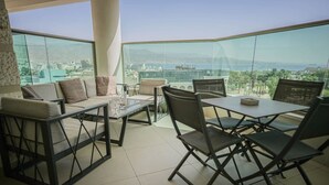 A modern dining area with a glass partition, a sofa, and a table with chairs. - Mamad Panoramic Red Sea | Chic 3BR Haven (Eilat)