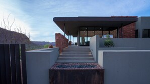 Un bâtiment moderne doté d’une entrée couverte, d’un escalier menant à l’entrée principale et offrant une vue sur le paysage environnant.