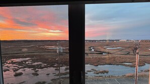 A view through a window of a landscape with a sunset, power lines, and a flat terrain. - Ocean Oasis - Beachfront Condo with breathtaking views (Hampton)