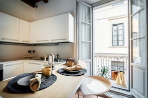 A kitchen with white cabinets, a wooden countertop, and a window with a view of a building and a balcony.
