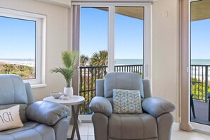 A balcony with two leather armchairs, a small table with a bowl and plates, and a potted plant.