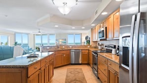 A modern kitchen with granite countertops, stainless steel appliances, wooden cabinets, and a large island.