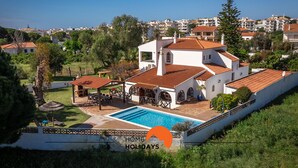 A villa with a swimming pool, outdoor seating, and a view of the surrounding neighborhood. - #213 Vila Roja Pé by Home Holidays (Albufeira)