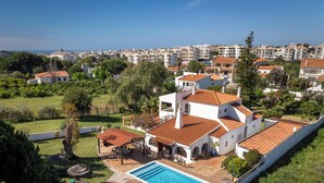 A large villa with a swimming pool, surrounded by lush greenery and a view of a coastal town. - #213 Vila Roja Pé by Home Holidays (Albufeira)