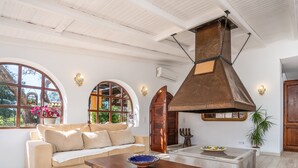 A spacious living area with a large chimney, arched windows, and a cozy seating arrangement. - #213 Vila Roja Pé by Home Holidays (Albufeira)