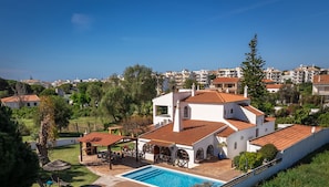 Una villa con piscina, mobiliario de exterior y vistas del vecindario.