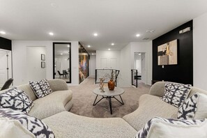 A modern living room with a sofa set, a coffee table, and a painting on the wall.