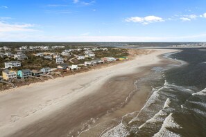 Une zone résidentielle côtière avec des maisons le long de la plage, un rivage sablonneux et des vagues qui se brisent sur le rivage.