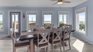 A dining area with a table set for four, wooden chairs, and a ceiling fan. - "Narwhal Nest" Newly remodeled, 5 bed/3 bath, oceanfront home! (Supply)