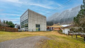 A modern building with a concrete facade, a gravel driveway, and a fenced area.