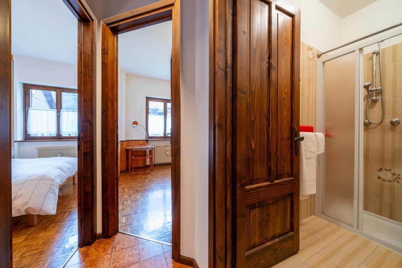 Une chambre avec une porte en bois, une salle de bain avec une douche en verre et une vue sur l’espace repas.