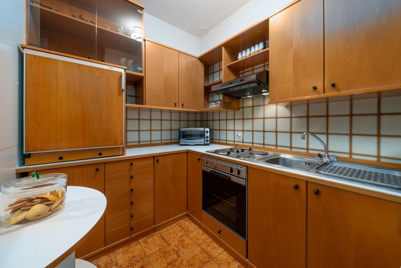 Een koelkast, een oven, een kookplaat, kookgerei, borden en bestek