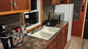 A kitchen with wooden cabinets, a granite countertop, a sink, a microwave, and a refrigerator.