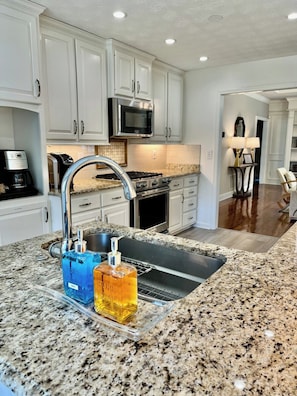 A kitchen with white cabinets, a stainless steel sink, and a granite countertop.