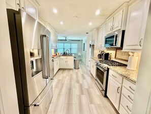 A modern kitchen with white cabinetry, stainless steel appliances, and a granite countertop.