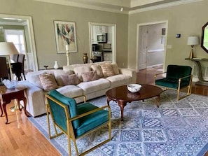 A living room with a sofa, two armchairs, a coffee table, and a patterned rug.