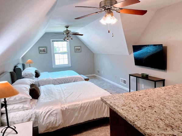 Une chambre à coucher avec un lit, un ventilateur de plafond, une télévision et une fenêtre.