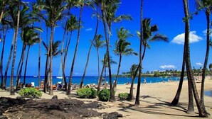A beach with palm trees, a clear blue sky, and a pool area. - Kolea Villas 15M, Luxury, Direct Beach Access (Waikoloa)