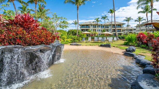 A resort with a waterfall, palm trees, and a pool area. - Kolea Villas 15M, Luxury, Direct Beach Access (Waikoloa)