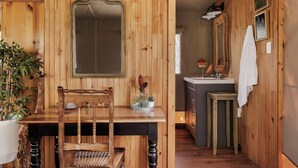 A wooden interior with a dining table, chairs, a mirror, a sink, and a towel hanging on the wall.
