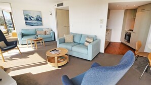 A modern living room with a sofa, armchair, coffee table, and a dining area with a table and chairs.