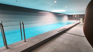 An indoor swimming pool with clear water, tiled walls, and a tiled floor.
