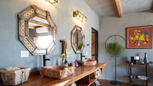 A bathroom with two large mirrors, a wooden vanity with a sink, and a floor lamp. - Casa Pavo Real en Viñedo El Pavo Real (San Miguel de Allende)