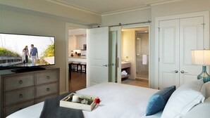 Een hotelkamer met een bed, een televisie, een dressoir en een badkamer zichtbaar door een open deur.