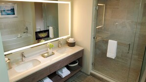 Een moderne badkamer met twee wastafels, een grote spiegel en een douche met glazen wanden.