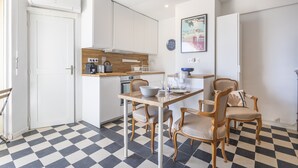 Une cuisine de taille réduite avec des meubles blancs, un plan de travail en bois et un carrelage à motifs.