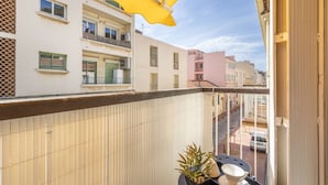 A balcony with a yellow umbrella, a potted plant, and a white bowl on a tray. - Studio Baldosa - Welkeys (Bandol)