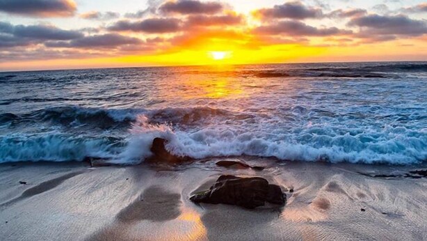 Una playa con olas y un atardecer.