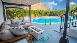 Un espacio al aire libre cubierto con piscina, asientos y una chimenea.