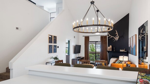 Una sala moderna con un sofá blanco, una araña y una chimenea.