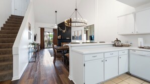 Una cocina moderna con armarios blancos, una isla central y una araña.