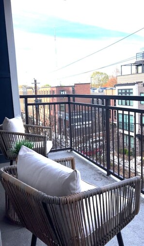 A balcony with wicker chairs and a view of buildings.